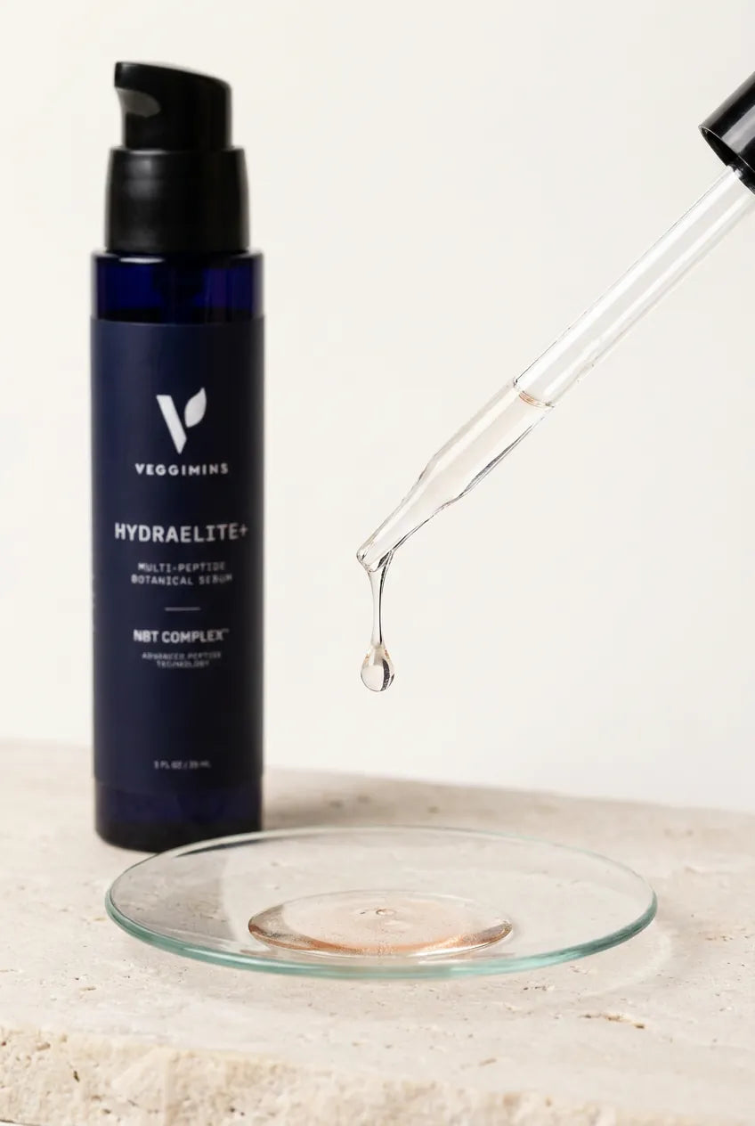 A drop of the clear HydraElite+ serum falling from a dropper into a glass dish